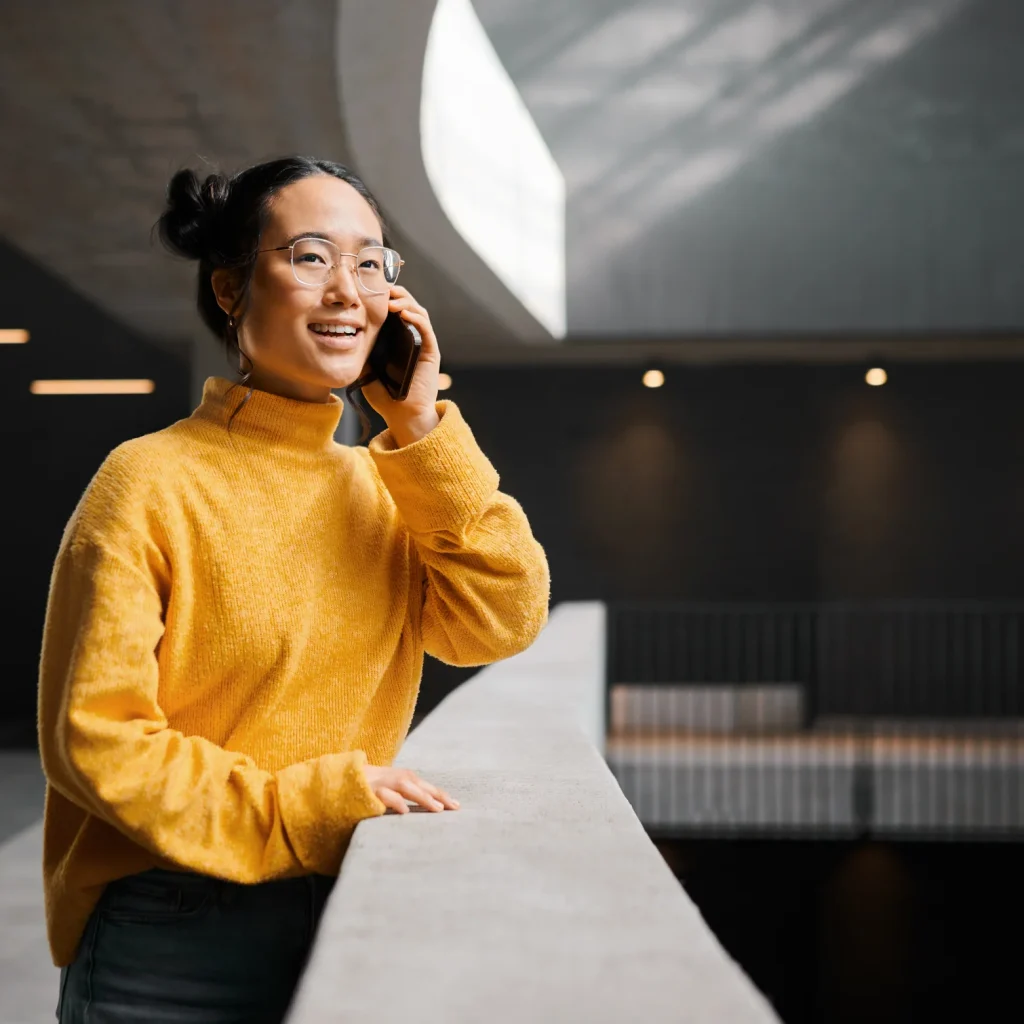 Femme au chandail jaune, au téléphone, accoudée à un comptoir
